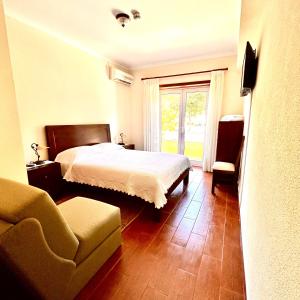 a bedroom with a bed and a chair and a window at A Cista in Vila da Ponte