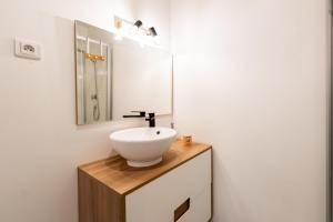 W łazience znajduje się biała umywalka i lustro. w obiekcie KASA CARO - Wifi & TV - Proche Centre ville w mieście Valenciennes