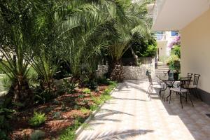 eine Terrasse mit Tischen, Stühlen und Palmen in der Unterkunft Apartment LU in Split
