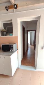 a kitchen with a microwave on a counter and a hallway at Alojamiento Parque Corralejo in Corralejo