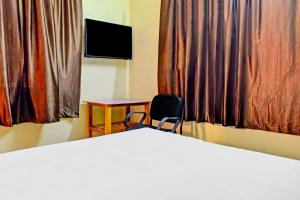 SPOT ON Hotel Seema Inn في Durg: غرفة نوم بسرير وطاولة وتلفزيون