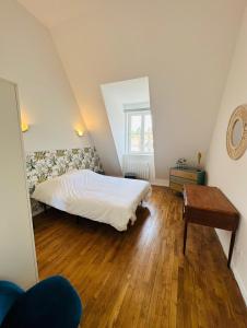 1 dormitorio con 1 cama y suelo de madera en L'Herboriste - Appartements meublés en Gien