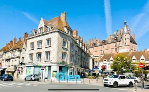 una calle de la ciudad con coches aparcados frente a un edificio en L'Herboriste - Appartements meublés en Gien