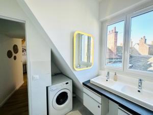 a bathroom with a sink and a washing machine at L'Herboriste - Appartements meublés in Gien