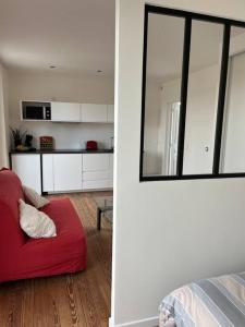 ein Wohnzimmer mit einem roten Sofa und einer Küche in der Unterkunft Apartment with balcony near Disneyland. in Esbly