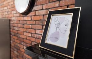 uma foto emoldurada de uma mulher numa mesa ao lado de uma parede de tijolos em Przytulny Loft W Uroczej Okolicy em Gliwice