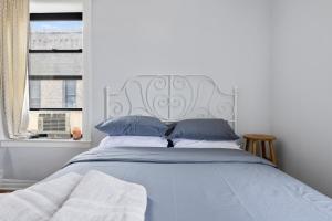 a blue bed with a white headboard and a window at Live Upper Manhattan on a Budget in New York