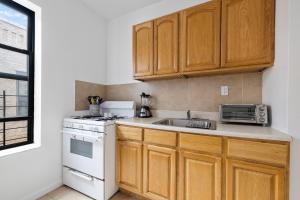 eine Küche mit Holzschränken, Spüle und Herd in der Unterkunft Live Upper Manhattan on a Budget in New York