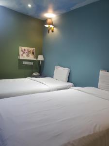 two white beds in a room with a blue wall at Boutique Hote123 in Kuala Lumpur