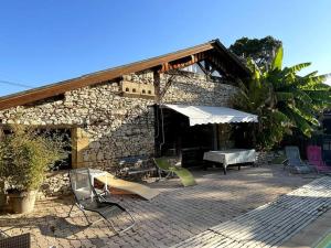 um edifício de pedra com um pátio com uma mesa e cadeiras em Gite de charme en pierres apparentes : Les Granges em Gardonne