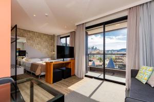 um quarto de hotel com uma cama e uma grande janela em AION 302- Apartamento Loft com Linda Vista Para o Mar de Bombinhas em Bombinhas