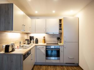 a kitchen with white cabinets and a sink and a refrigerator at Adlernest in Riezlern