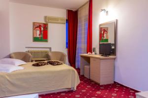 ein Hotelzimmer mit einem Bett und einem TV in der Unterkunft Hotel Dambovita in Târgovişte