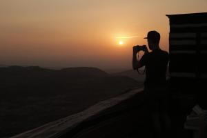 Ein Mann, der den Sonnenuntergang fotografiert. in der Unterkunft Plaza View Hostel in Taiyiba