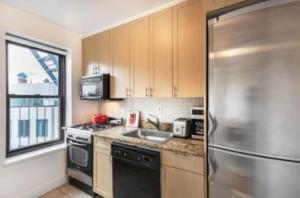 uma cozinha com um frigorífico de aço inoxidável e um lavatório em Warm and Comfortable 3 BR em Nova York