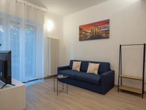 ein Wohnzimmer mit einem blauen Sofa und einem TV in der Unterkunft [IHost Apartment] - Rogoredo 27 in Mailand