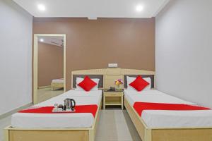 two beds with red pillows in a room at Hotel Padmini Near Lakdikapool Metro Station in Hyderabad