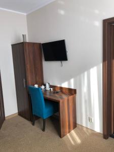Zimmer mit einem Schreibtisch, einem TV und einem blauen Stuhl in der Unterkunft Świdnica Kolonia noclegi in Świdnica