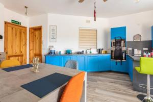 une cuisine avec des placards bleus et une table avec des chaises dans l'établissement Gozo Escape 2-Bed Apartment in Marsalforn, à Marsalforn