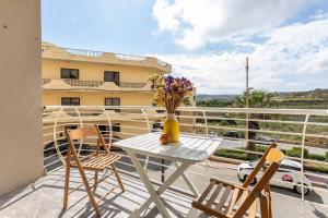 d'une table avec des chaises et un vase de fleurs sur le balcon. dans l'établissement Gozo Escape 2-Bed Apartment in Marsalforn, à Marsalforn