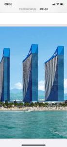 Deux grands bâtiments avec l'océan en face d'eux dans l'établissement Orbi City Blok D, à Batoumi