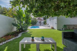 een witte tafel in een tuin met een zwembad bij VT Villa Carmelo 3BDR Private Pool in Torremolinos