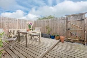 a wooden deck with a table and chairs and a fence at Print Rooms, Leiston in Leiston