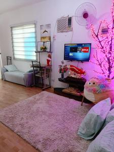 uma sala de estar com uma parede rosa e uma televisão em Amigas Lodge Transient em San Felix