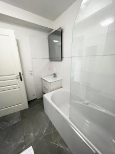 La salle de bains blanche est pourvue d'une baignoire et d'un lavabo. dans l'établissement Design Apartment Disneyland Paris, à Chessy