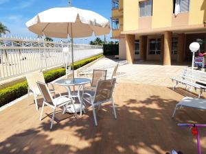 une terrasse avec une table, des chaises et un parasol dans l'établissement Aqui é pé na areia, à Santos