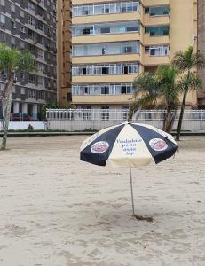 - un parasol bleu et blanc sur une plage de sable dans l'établissement Aqui é pé na areia, à Santos