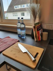 two bottles of wine and a knife on a cutting board at ALA Living Stil-Voll Apartment gemütlich & modern mit extra großem Parkplatz, Balkon, Arbeitsplatz & eigenem Eingang, 5min zur Ulm Messe und Autobahn in Neu Ulm