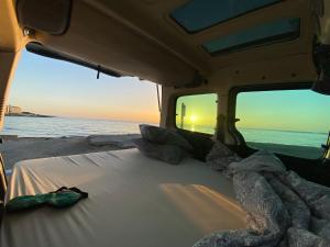 a bed in the back of a van looking out at the ocean at CamperTF - old but lovable mini caravans in Tenerife in El Médano