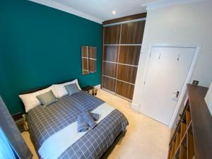 een slaapkamer met een bed en een blauwe muur bij 3-Bed Flat Central London, 6 Min Walk from King's Cross Station in Londen