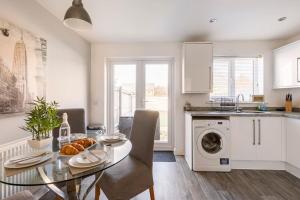 a kitchen and dining room with a table and a dishwasher at Entire Home in Swansea, near Swansea.dotcom Stadium, Sleeps 4, by Properties by O & G in Bon-y-maen