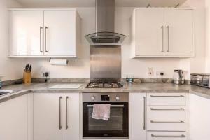 a kitchen with white cabinets and a stove top oven at Entire Home in Swansea, near Swansea.dotcom Stadium, Sleeps 4, by Properties by O & G in Bon-y-maen
