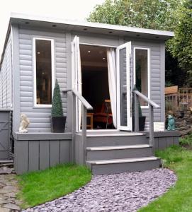 ein kleines graues Haus mit einer Veranda und einer Treppe in der Unterkunft The Garden Room in Knighton