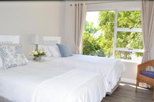 two beds in a white bedroom with a window at Ocean Pearl Hermanus - 5 Bedrooms in Hermanus