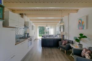 eine Küche und ein Wohnzimmer mit einem Sofa und einem Tisch in der Unterkunft Vakantiehuis Heideblick - car-free park - Callantsoog in Callantsoog
