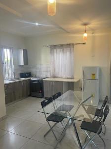 una cocina con mesa de cristal y sillas. en AlanVal Apartments, en Accra