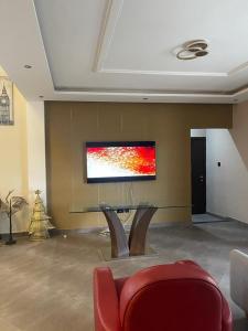 a living room with a table and a television on a wall at AlanVal Apartments in Accra