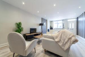 a living room with two chairs and a table and a television at Stunning 5BR house wgarden & terrace, SE London in London