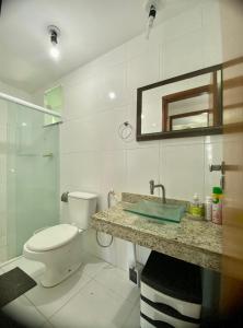 uma casa de banho com um WC, um lavatório e um espelho. em Charmoso 1/4 com linda vista em Ilhéus
