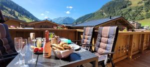 einen Tisch mit Weingläsern und Essen auf dem Balkon in der Unterkunft Hochalmbahnen Chalets Rauris 1-16 WE2, Maislaufeldweg 1p OG in Rauris