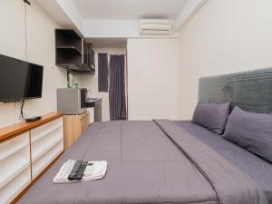 una camera con un grande letto e una TV di Apartemen Green Lake View Ciputat by Alfa Rooms a Pondokcabe Hilir
