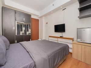 una camera con letto e TV a schermo piatto di Apartemen Green Lake View Ciputat by Alfa Rooms a Pondokcabe Hilir