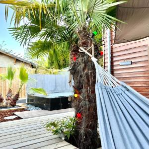 a hammock in front of a house with a palm tree at La Villa Canopée - Piscine chauffée-Fibre-Clim-Jacuzzi in Gujan-Mestras
