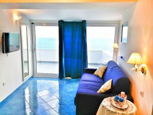 a living room with a blue couch and a large window at Casa Vacanze La Rosa Del Mare in Amalfi