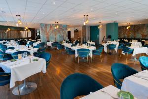 a dining room with white tables and blue chairs at Hôtel & Restaurant des Remparts in Rochefort