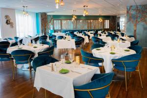 ロシュフォールにあるHôtel & Restaurant des Rempartsのダイニングルーム(白いテーブル、青い椅子付)